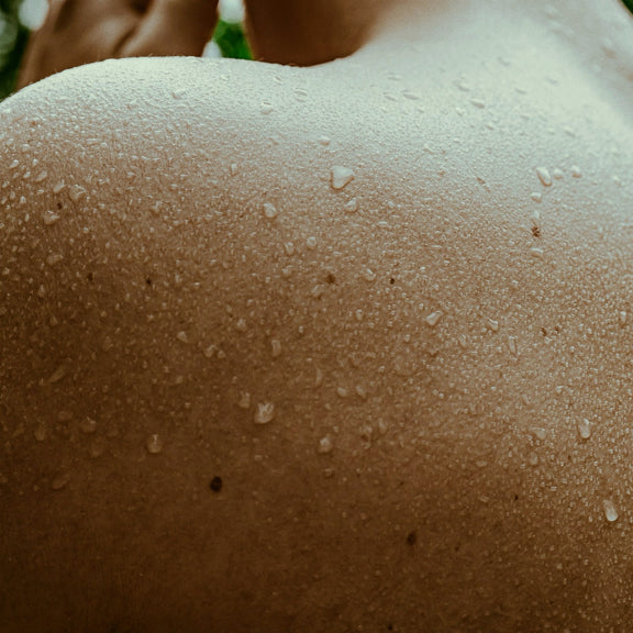 Close view of a bare shoulder and upper back beaded with sweat after a sauna